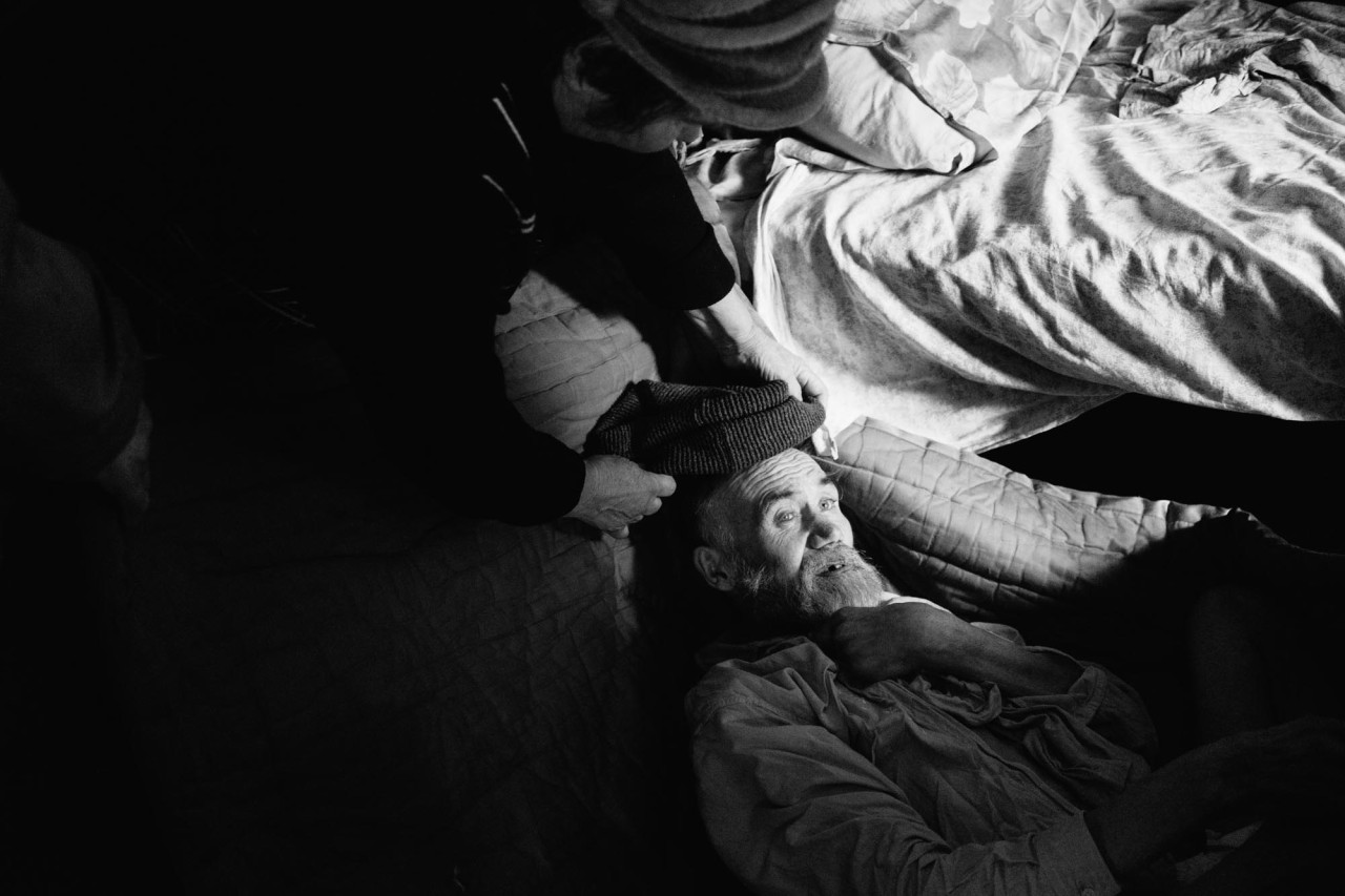 Ивана готовят для переноски в баню.
Иван — электрик. После удара током его частично парализовало, Валентина забрала его из больницы в приют